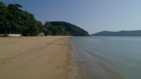 Peaceful-empty-sandy-beach-with-calm-sea-waves-on-shore-in-Thailand,-aerial