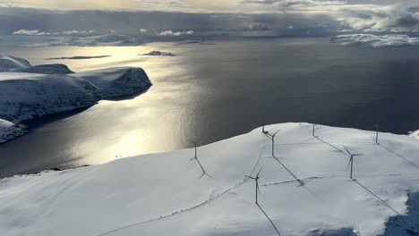 Aerial flyover in a helicopter of wind turbines on a mountain overlooking the sea in northern Norway