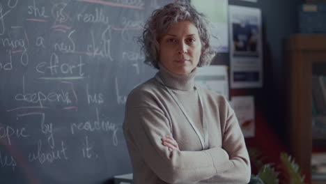 portrait of mid-aged female teacher in front of blackboard during english class