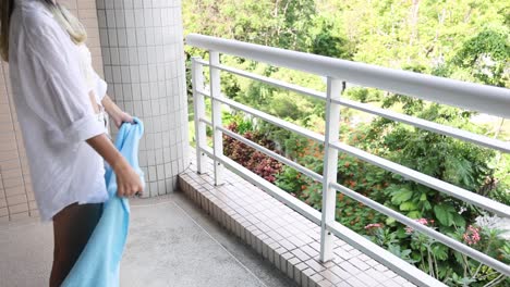 person airing out a towel outdoors on a balcony