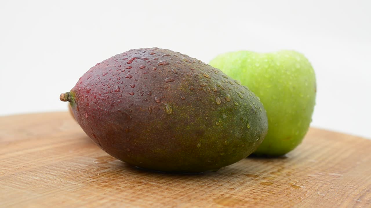 Frutta su un tagliere di legno. Mango, mela e kiwi. Riprese in movimento.