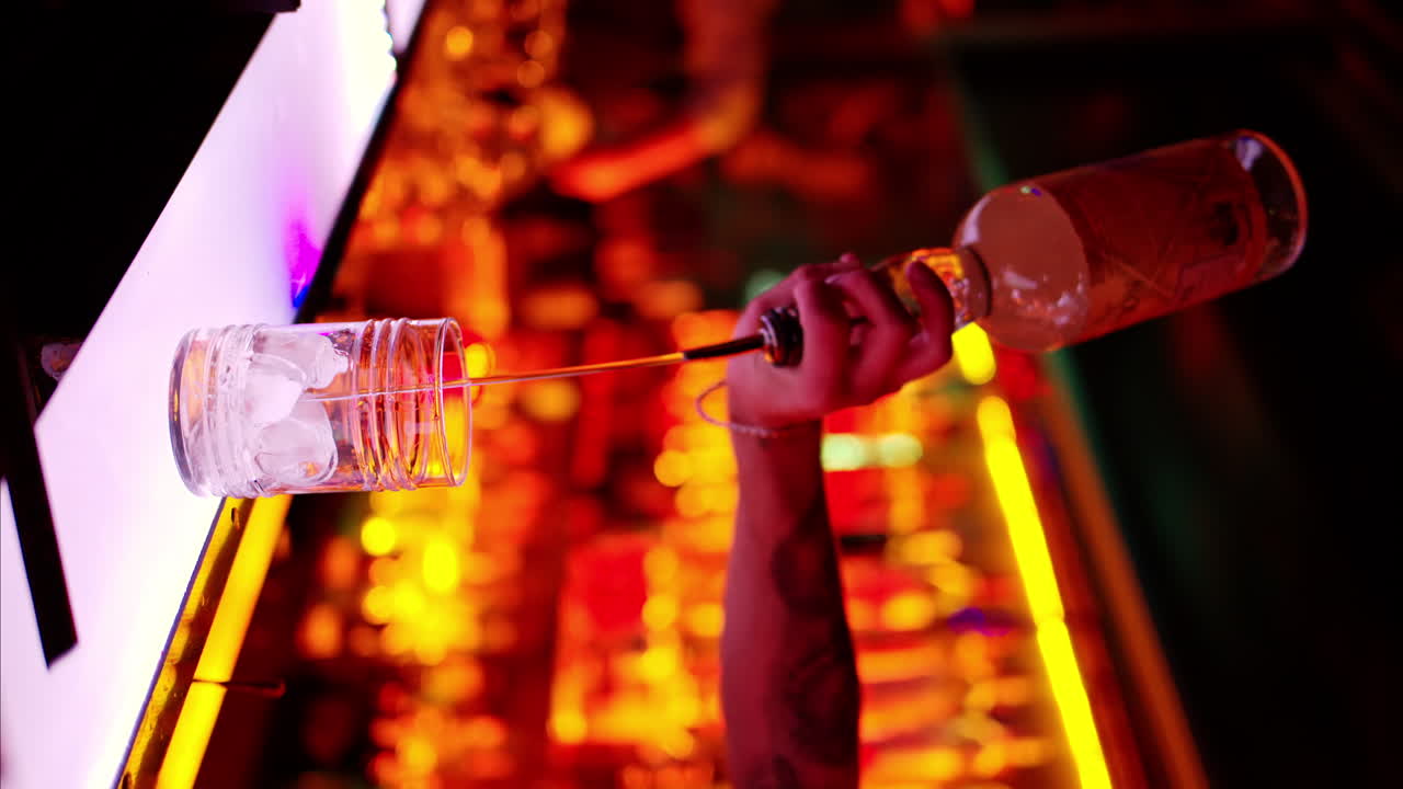 Barman making cocktails with whiskey liquor alcohol at the bar at night with red neon lights, slow motion