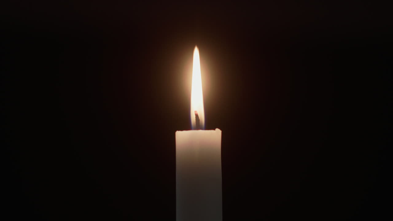 Une bougie brûle dans la pièce sombre