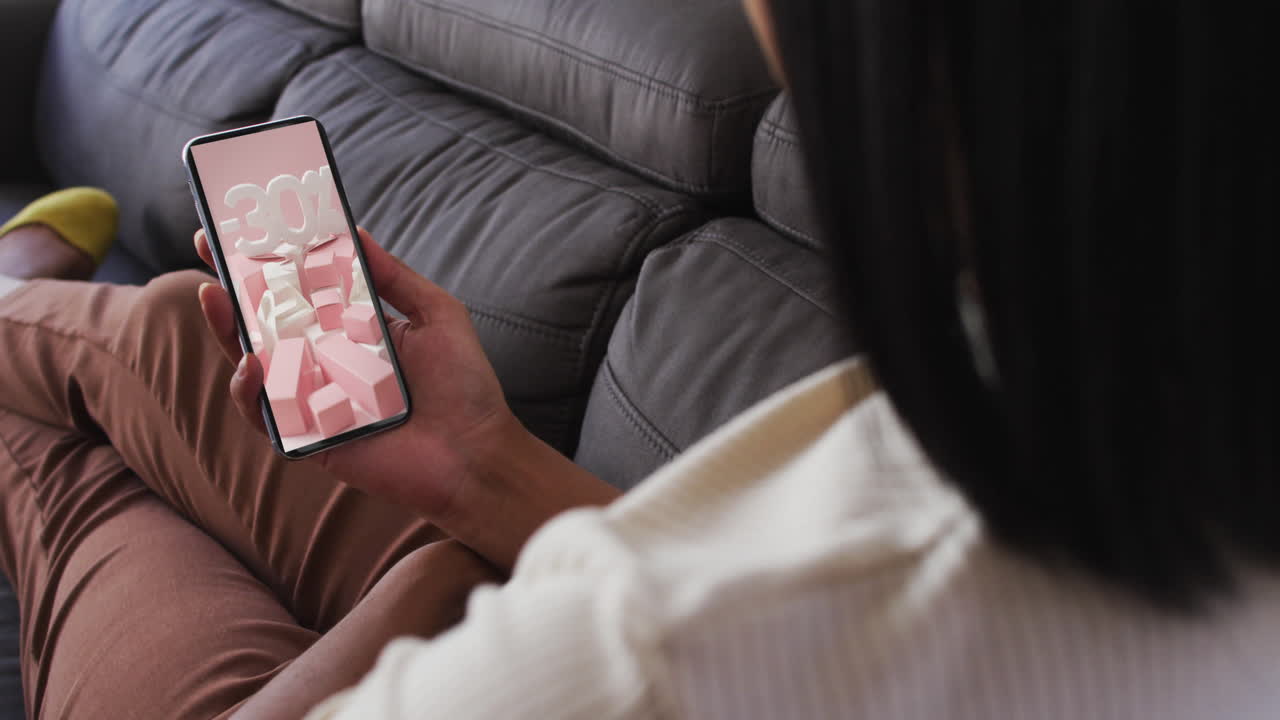 Donna birazziale sul divano che usa lo smartphone per lo shopping online, al rallentatore.