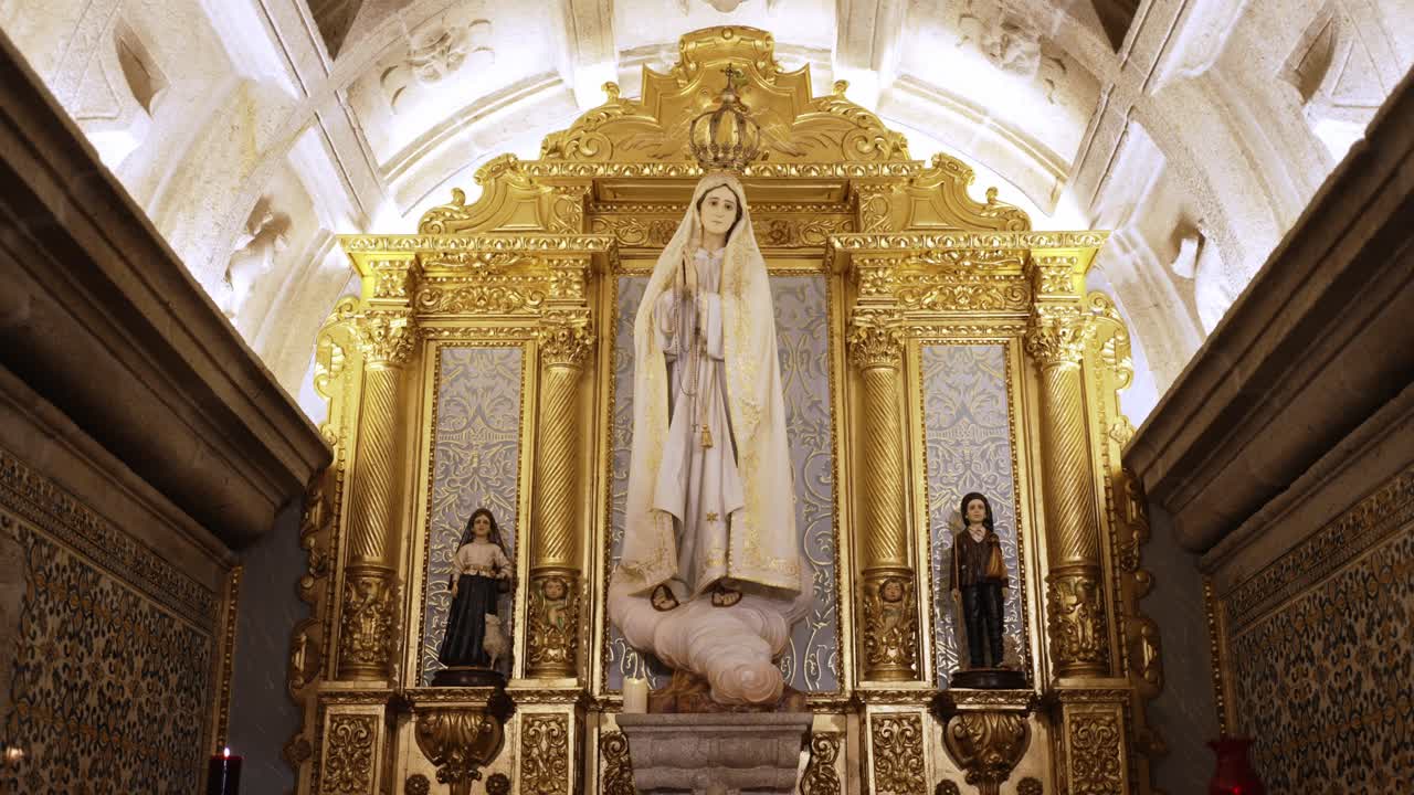 Golden church altar of Our Lady of Fátima flanked by statues of shepherd children
