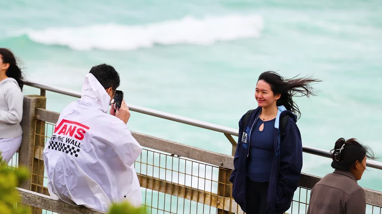 People taking pictures by the ocean