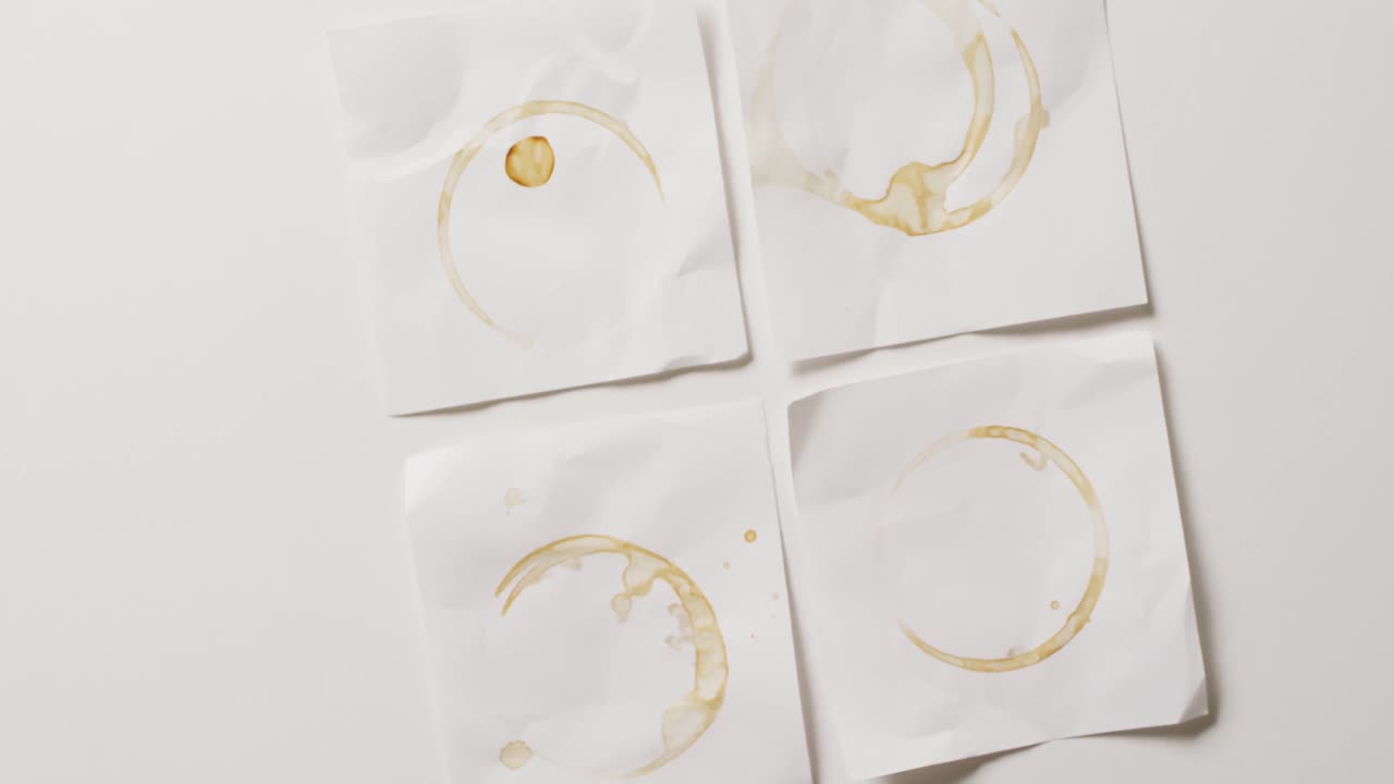 ⁇  배경 에 커피 컵 얼룩 이 있는 4 개의 종이 조각 의 클로즈업 비디오