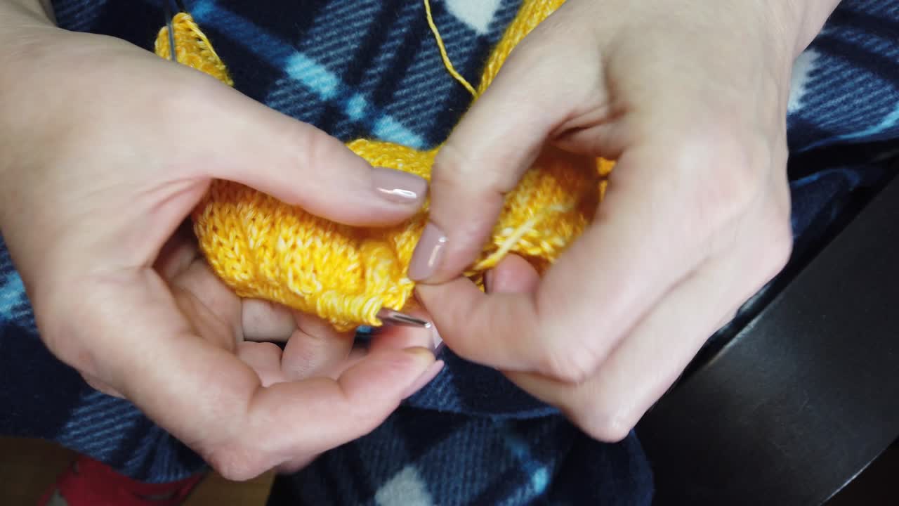 manos de mujeres tejer chaqueta de lana con agujas de tejer. vista superior, primer plano de las manos y tejer.