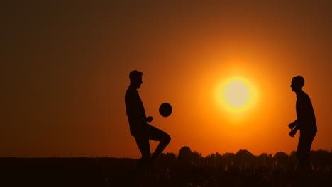 Zwei-Jungen-Spielen-Bei-Sonnenuntergang-Fußball.-Silhouette-Von-Kindern,-Die-Bei-Sonnenuntergang-Mit-Einem-Ball-Spielen.-Das-Konzept-Einer-Glücklichen-Familie.