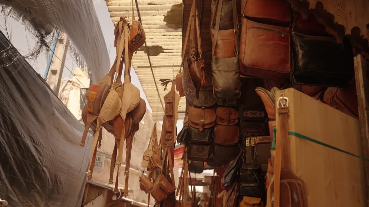 Handcrafted leather bags and satchels hang for sale in a traditional Moroccan market
