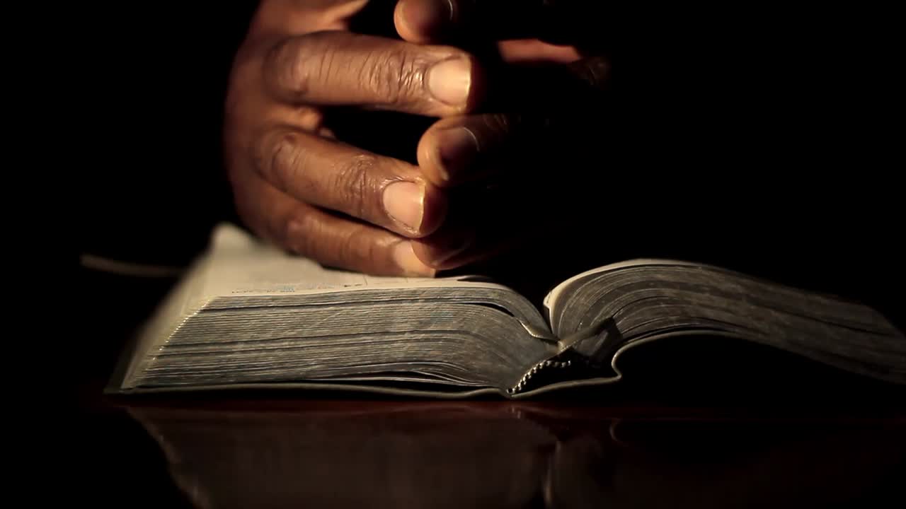 Prière, main sur la bible, sur fond noir avec des personnes, séquence vidéo