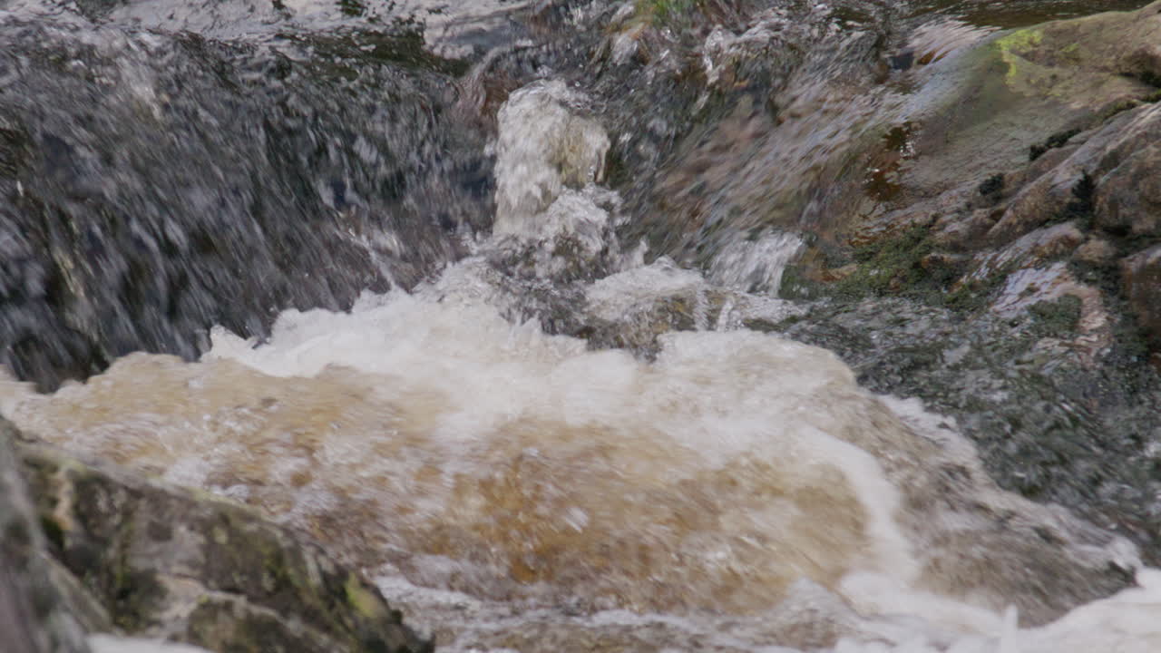 Violent splash of mountain stream water colliding with rock surface in slow motion revealing nature’s raw intensity