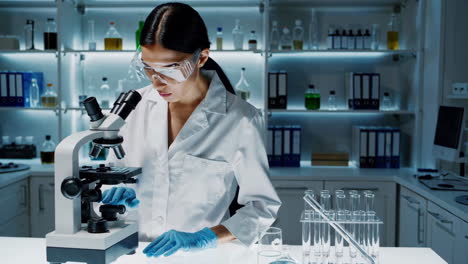 científica que usa el microscopio en un laboratorio