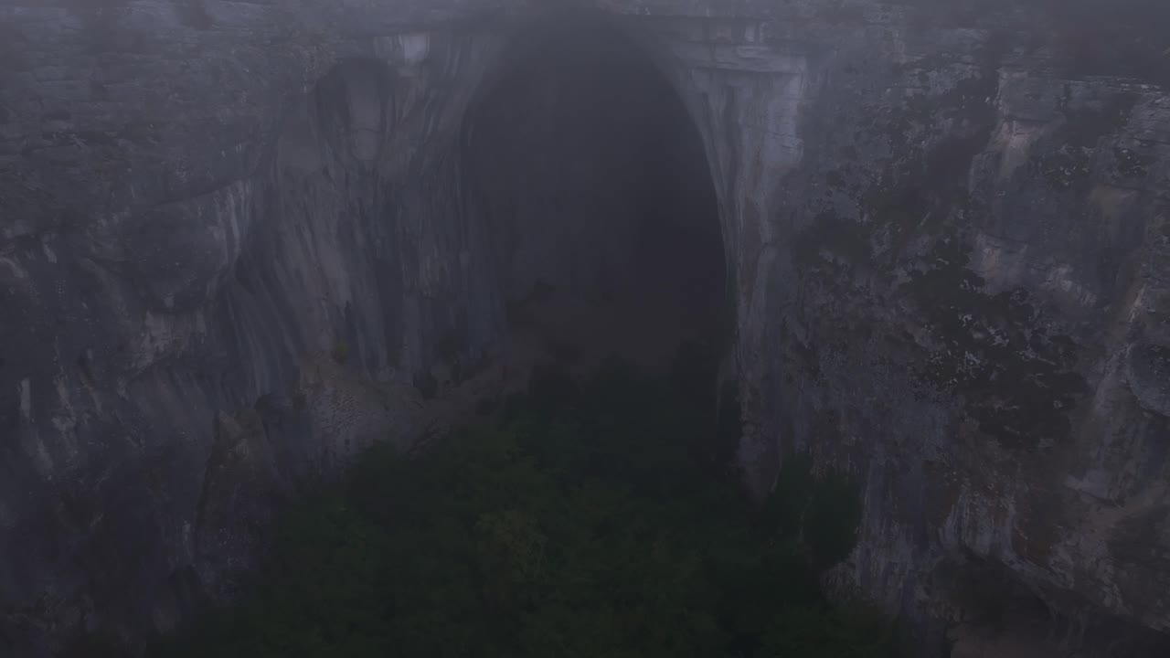 Majestic cave entrance towers above forested rocks, Bulgaria