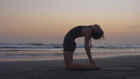 mujer practicando yoga en la playa al atardecer