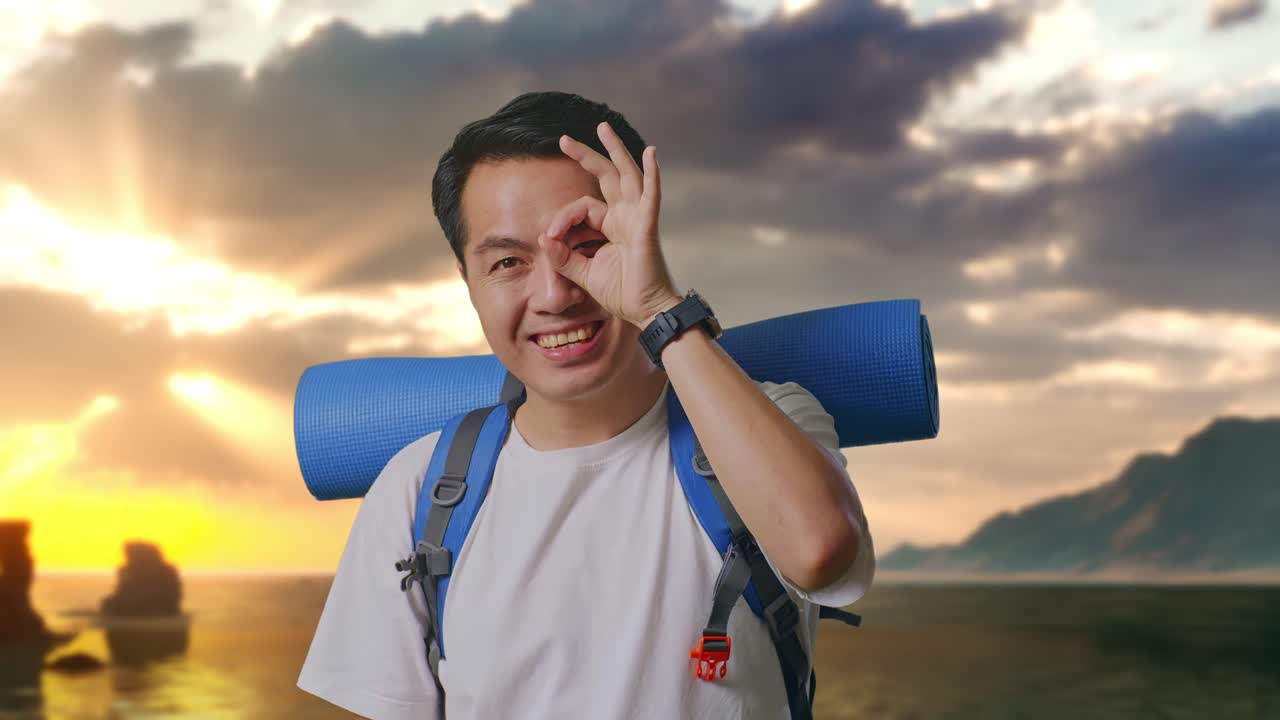 Close Up Pendaki Pria Asia Dengan Ransel Mendaki Gunung Tersenyum Dan Menunjukkan Tanda Ok Dengan Jari Di Atas Mata Di Pantai
