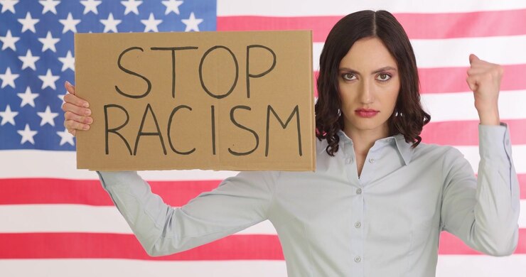 Woman shows stop racism sign shaking fist against american flag