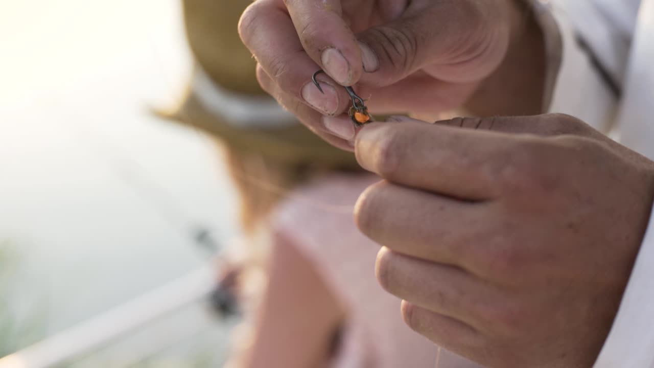 Primo piano di mani maschili che sciolgono un nodo da pesca sull'amo