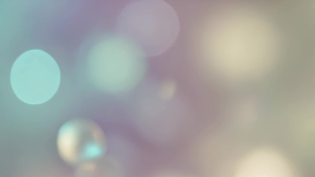 Riproduzione in corso, una coppia di goccioline perlescenti fluttua su uno sfondo sfumato mentre il bokeh si scalda.