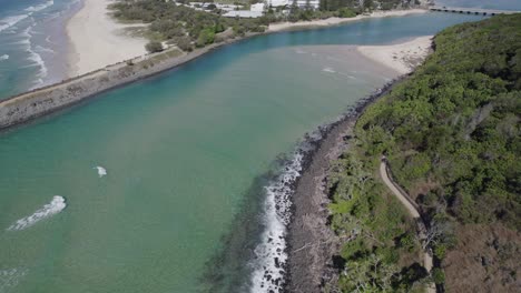 drone flying towards rocky coastal headland of burleigh head national park in gold coast, queensland, australia