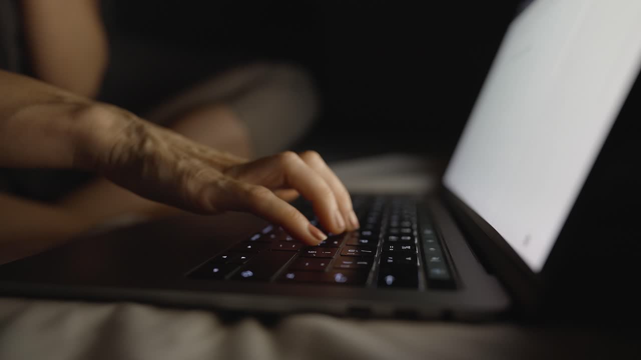 una mujer en la cama escribiendo en su computadora portátil un correo electrónico