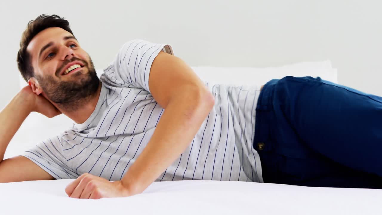 Uomo sorridente che salta sul letto in camera da letto