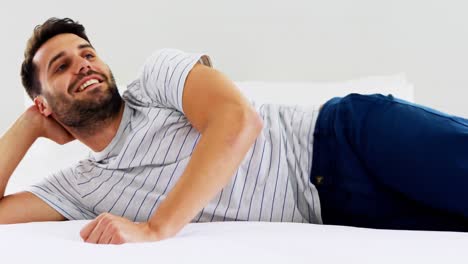 hombre sonriente saltando en la cama en el dormitorio