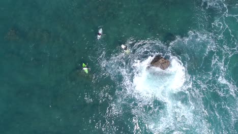 Wide-top-down-shot-from-aerial-drone-view-of-surfers-waiting-for-a-wave