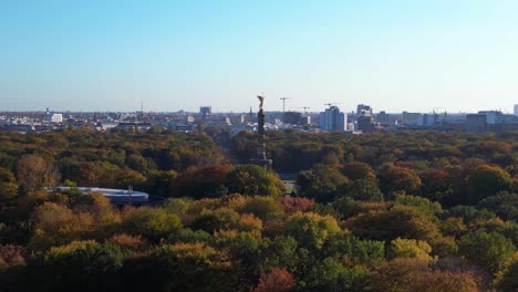 iconic berlin victory column rising above the vibrant autumn foliage of tiergarten park, with the cityscape in the background. lovely aerial view flight speed ramp hyper motion time lapse