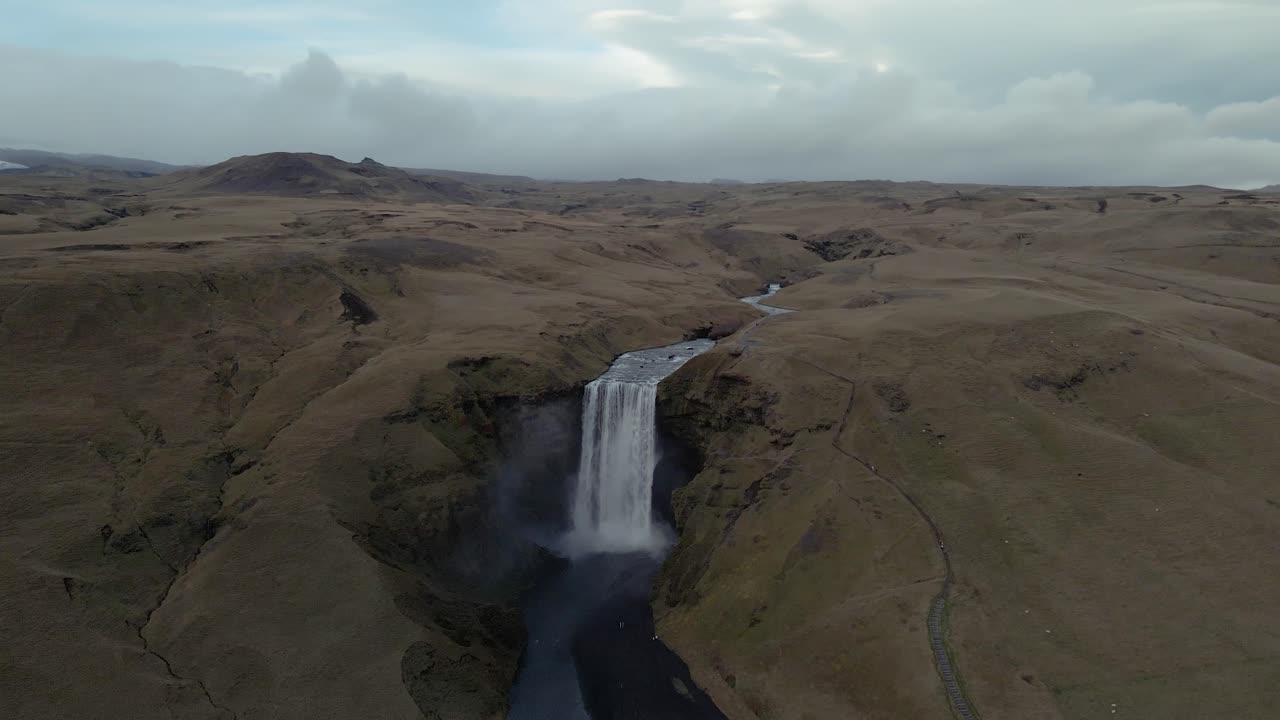 un dron desciende y se inclina sobre la cresta de la cascada skógafoss