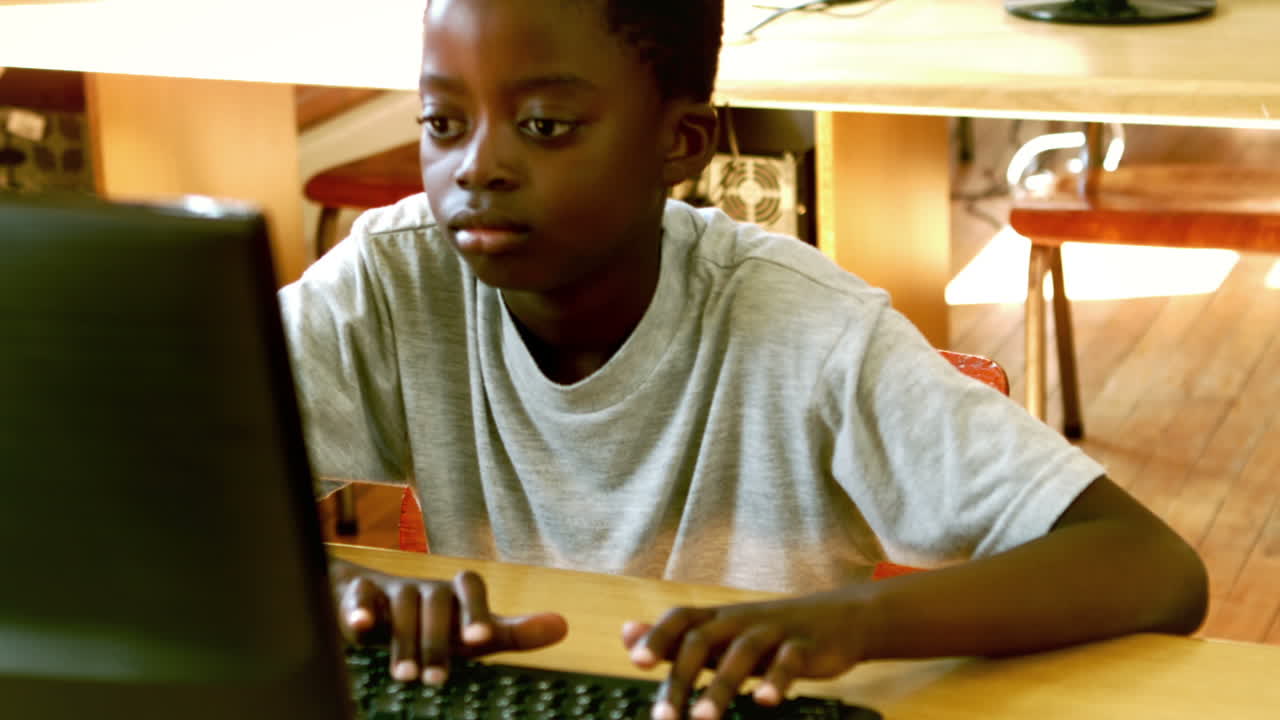Cute little pupil looking at laptop in classroom