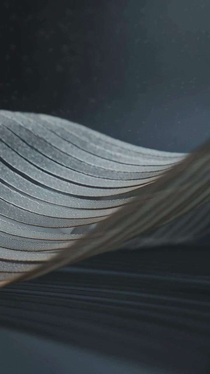 Vertical video: Lighting from right causing pleated sheet waving on table showing stripes and dust