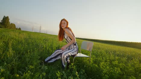 woman in striped jumpsuit sitting in a field at sunset