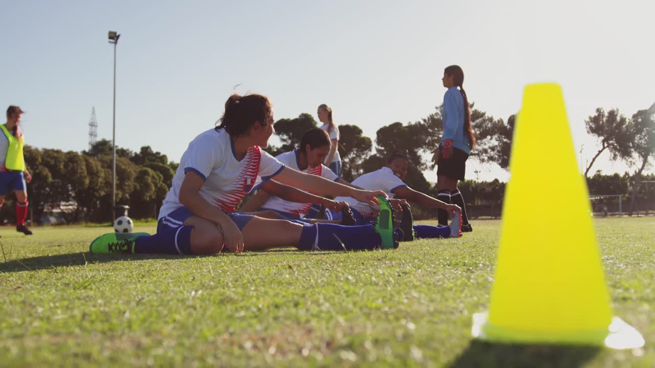 여자 축구 선수 들 이 축구장 에서 훈련 하기 전 에 스트레칭 하고 있다. 4k