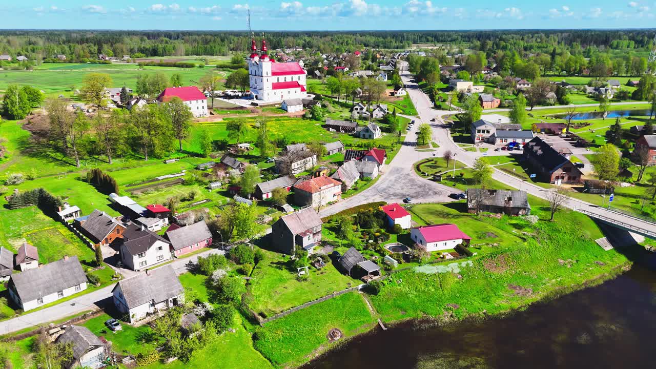 Aerial shot of a tranquil village in Lithuania, showcasing houses and lush green fields