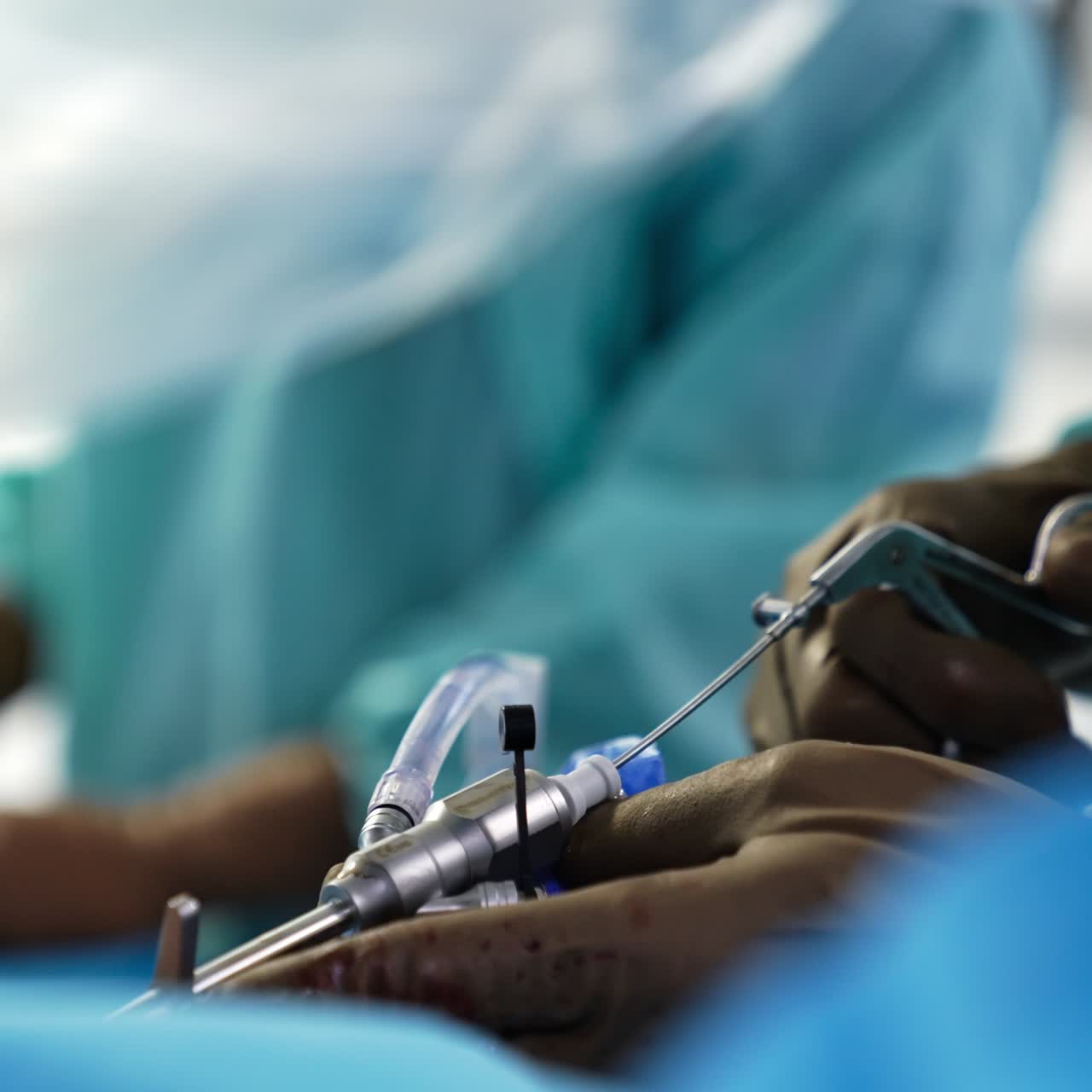 Usage of special surgery instruments during the operation. Hands in brown rubber gloves apply medical tool for neurosurgery. Blurred background