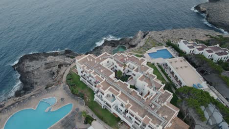 establishing aerial view rising birdseye above mallorca holiday resort on mediterranean coastal cliff edge