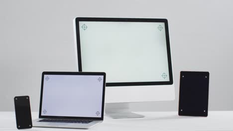 Video-of-laptop,-smartphone,-tablet-and-computer-on-white-table-with-copy-space-in-office