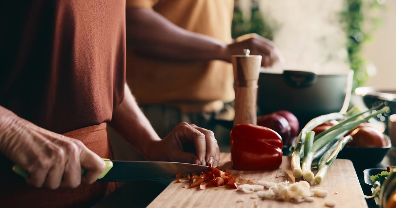 Person Chopping Red Bell Pepper on Wooden Cutting Board in Kitchen