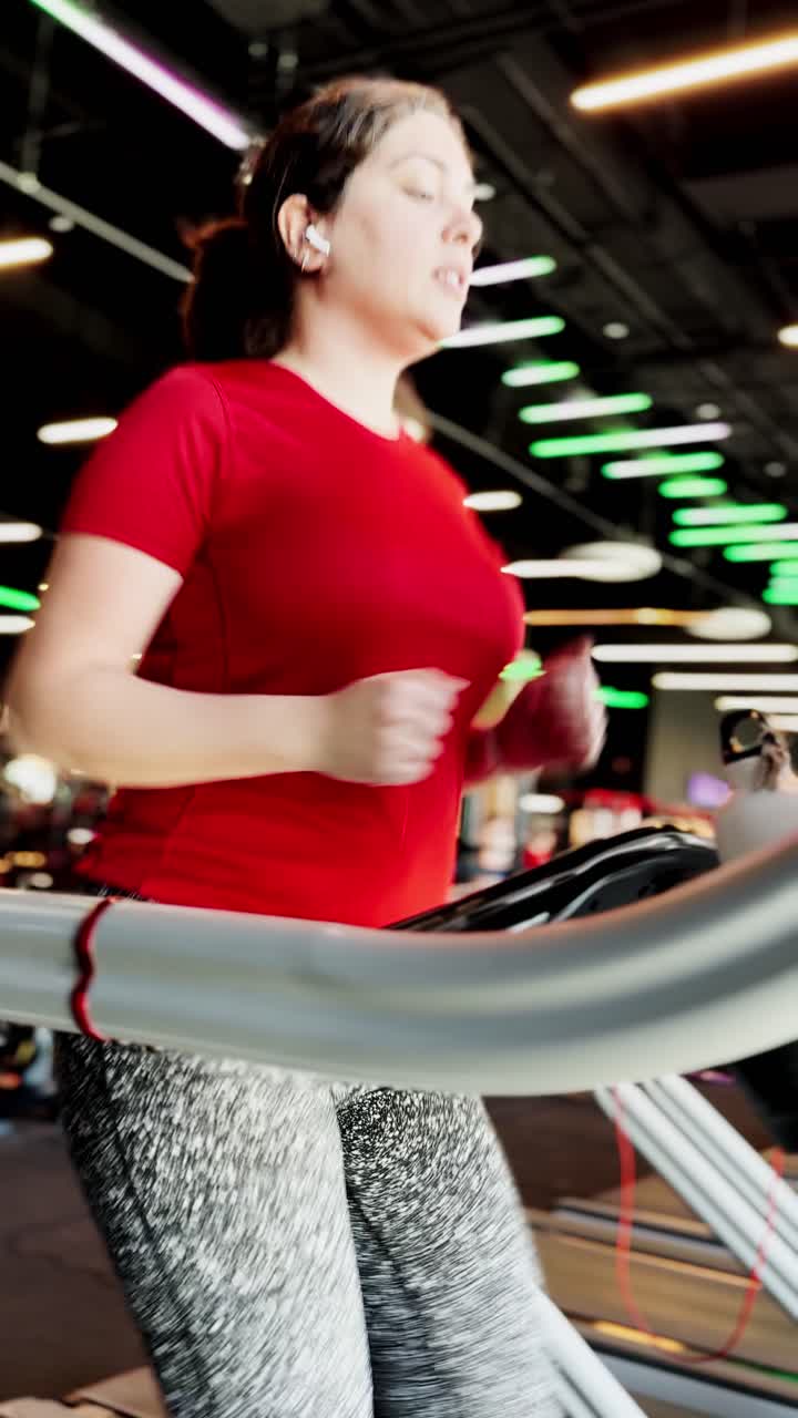 Spor salonunda koşu bandında koşan genç kadın
