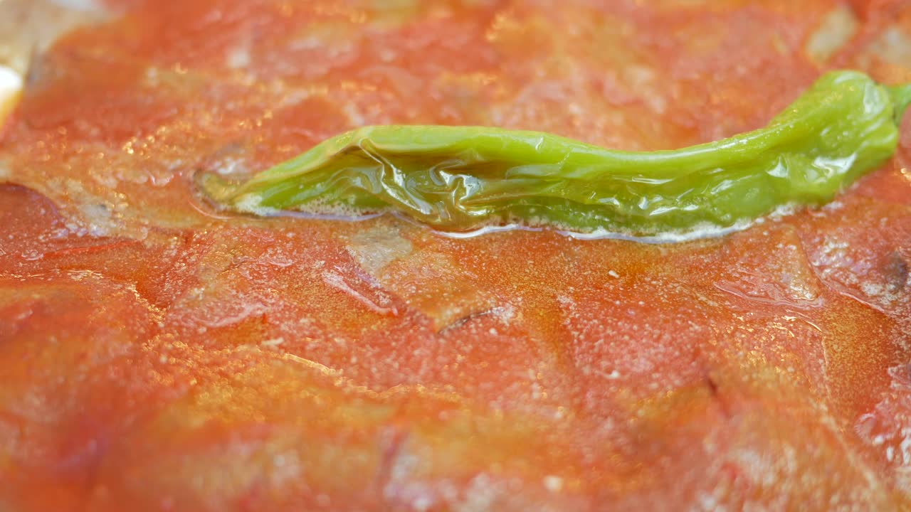 Close-up of a dish with tomato sauce, meat, and green pepper