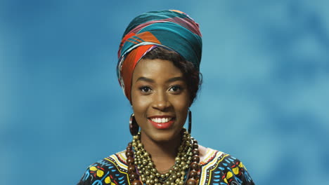 Close-up-view-of-African-American-young-woman-in-turban-and-traditional-clothes-smiling-and-looking-at-camera