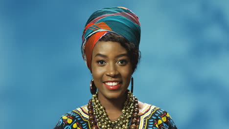 close-up view of african american young woman in turban and traditional clothes smiling and looking at camera