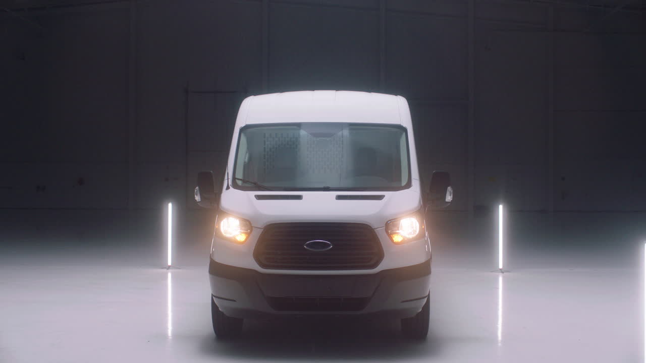 A white cargo van sits in an empty warehouse.