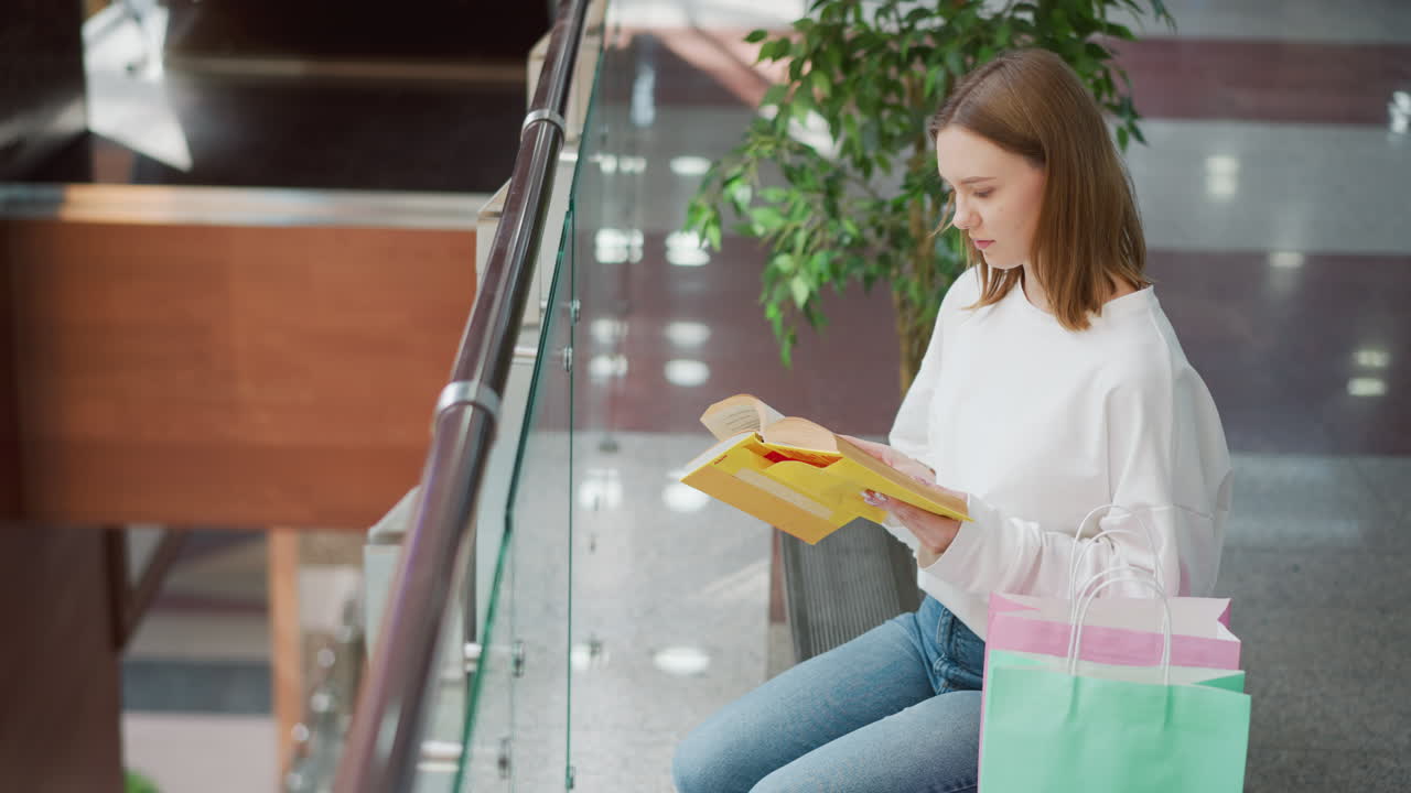 una mujer joven leyendo un libro en un centro comercial