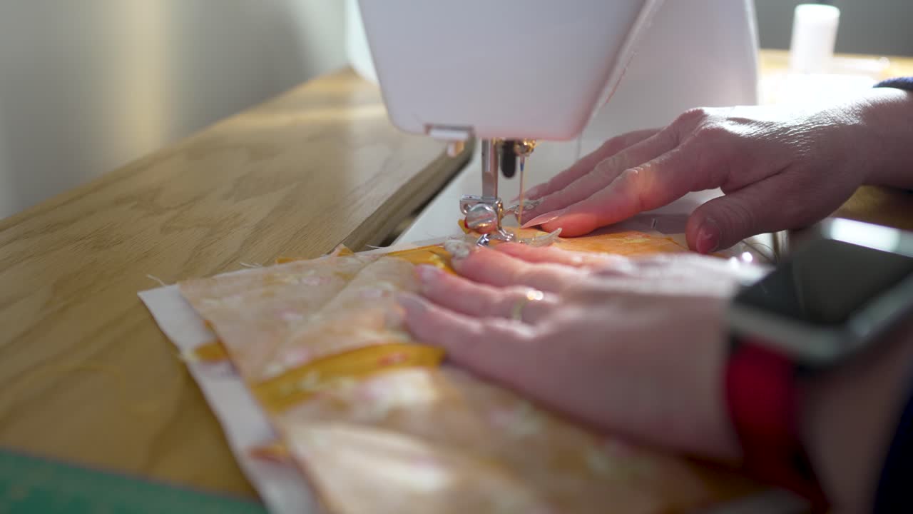 Sewing machine in slow motion stitching a homemade potholder together - side view ORANGE SCRAPS SERIES