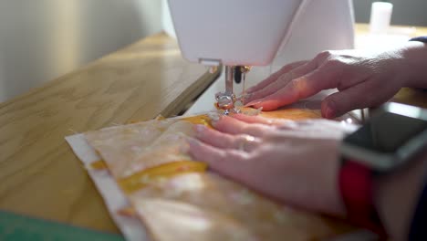sewing machine in slow motion stitching a homemade potholder together - side view orange scraps series