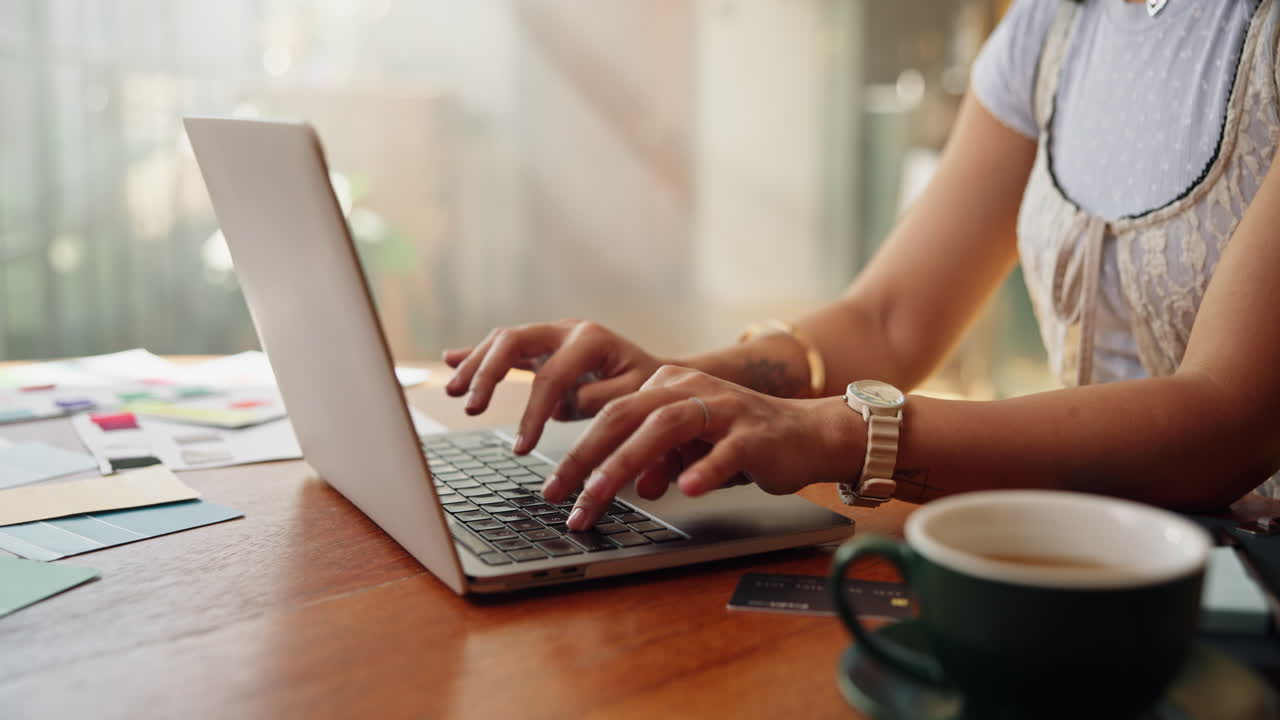 Donna che digita al laptop a un tavolo di legno con un caffè