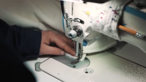 Primer-Plano-De-Las-Manos-De-Una-Mujer-Cosiendo-Tela-En-Una-Máquina-De-Coser-De-Fábrica-Para-Hacer-Una-Funda-Para-Un-Colchón