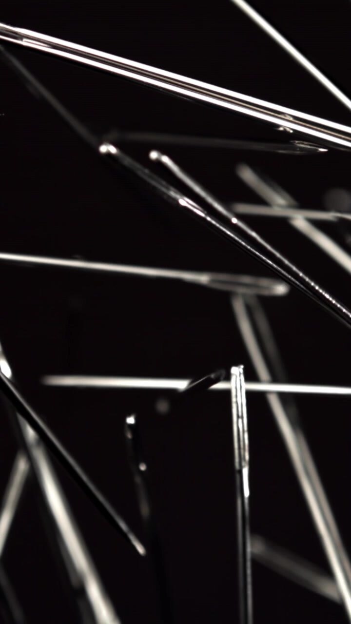 Sharp Metal Sewing Needles Focusing on a Black Surface
